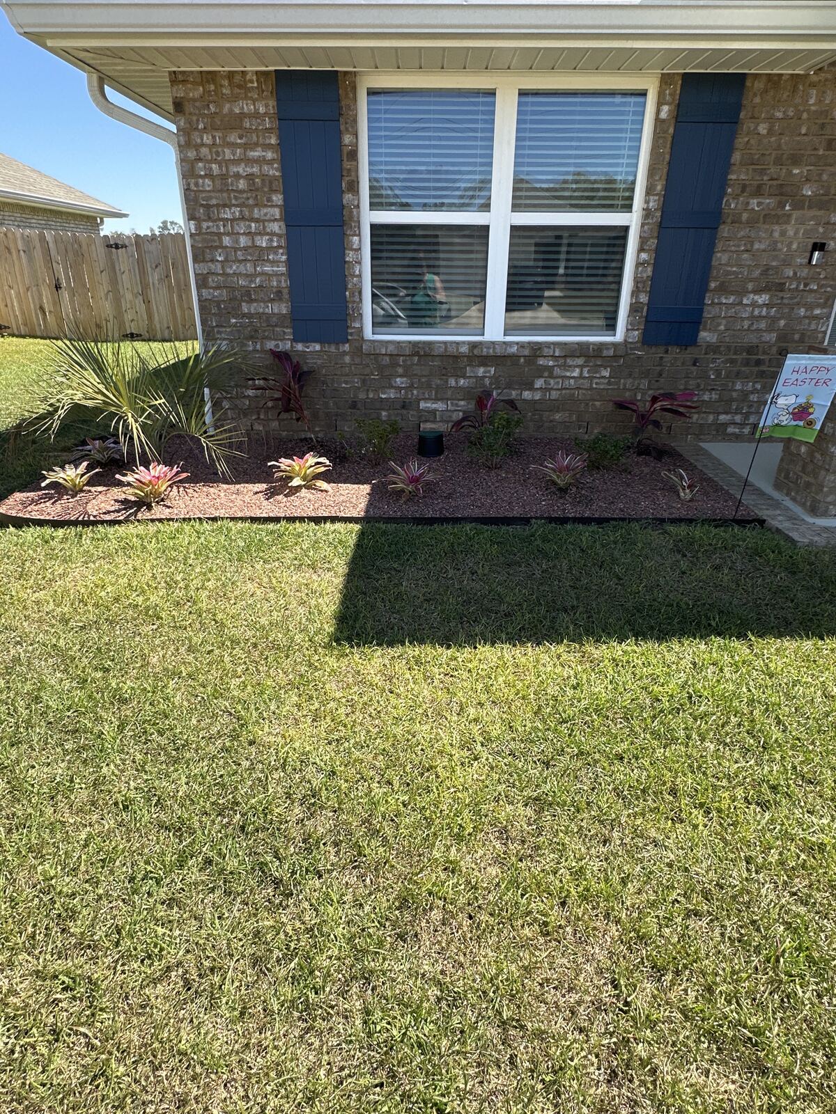 New mulched bed and plantings along a brick house front